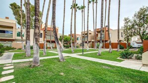 Un quartier résidentiel avec des immeubles modernes, des palmiers et une pelouse bien entretenue.