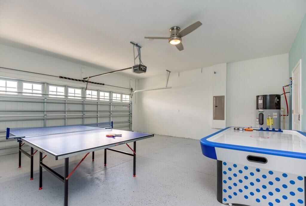 A spacious room with a ping pong table, a ceiling fan, and a projector.