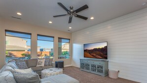 A living room with a large flat-screen TV, a ceiling fan, and a sofa with patterned cushions. - Sand Hollow 3370 | Private Pool, Hot Tub, Ping Pong, and near Sand Hollow Reservoir (Hurricane)