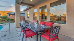 An outdoor patio with a table and chairs, large windows, and a pool. - Sand Hollow 3370 | Private Pool, Hot Tub, Ping Pong, and near Sand Hollow Reservoir (Hurricane)