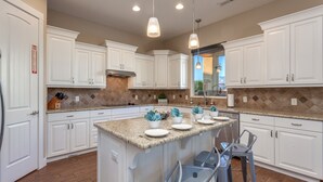 A modern kitchen with white cabinets, granite countertops, and pendant lighting. - Sand Hollow 3370 | Private Pool, Hot Tub, Ping Pong, and near Sand Hollow Reservoir (Hurricane)