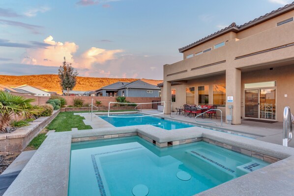 A swimming pool area with a patio, a covered seating area, and a view of the surrounding landscape. - Sand Hollow 3370 | Private Pool, Hot Tub, Ping Pong, and near Sand Hollow Reservoir (Hurricane)