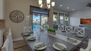 A dining area with a large clock, a chandelier, and a view of the outside. - Sand Hollow 3370 | Private Pool, Hot Tub, Ping Pong, and near Sand Hollow Reservoir (Hurricane)