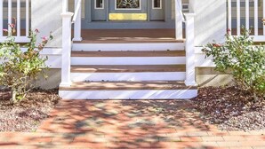 Une maison à deux étages avec un porche à l’avant, une porte d’entrée dotée de panneaux de verre et un petit escalier menant à l’entrée.