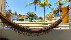 A hammock in a hotel courtyard with palm trees and buildings in the background. - Just a few steps from the beach - Ground-floor 2-bedroom apartment, swimming pools, AC, Wi-Fi, garage (Fortaleza)