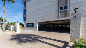 A building with a covered parking area, a palm tree, and a clear sky.