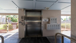 An elevator with a 'Going Out' sign, a security keypad, and a metal box on the wall.