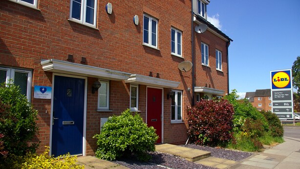 A red brick building with a blue door, a red door, and a satellite dish. - Caspian House (4 Bedrooms) - Serviced Accommodation (Grimsby)