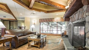 Un salon chaleureux avec une cheminée, un plancher en bois et un canapé en cuir.