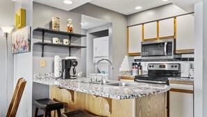 Eine moderne Küche mit Granit Arbeitsplatten, Edelstahlgeräten und Holzschränken.