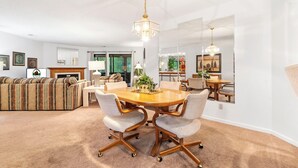 A spacious living room with a large sofa, a dining table with chairs, and a chandelier. - 2 Bed, 2 Bath with Screened Lake View Patio! (Branson)