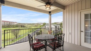 A balcony with a round table and chairs, a ceiling fan, and a view of a green landscape. - Family Escape w/ Balcony Views | Near 76 Strip | Branson Attractions (Branson)