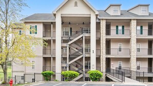 A multi-story apartment building with a central staircase, balconies, and a parking area. - Family Escape w/ Balcony Views | Near 76 Strip | Branson Attractions (Branson)