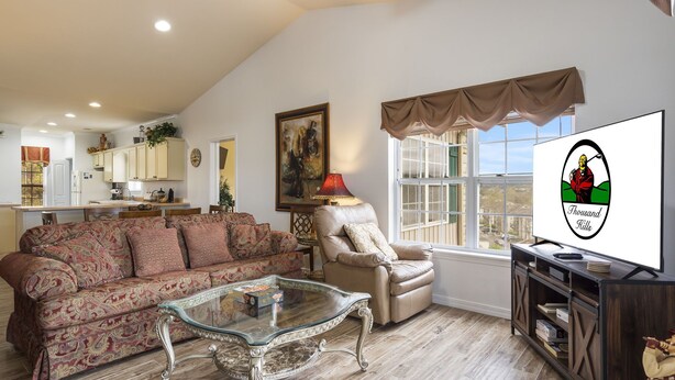 A spacious living room with a patterned sofa, a glass coffee table, a leather armchair, and a view of the kitchen in the background. - Family Escape w/ Balcony Views | Near 76 Strip | Branson Attractions (Branson)