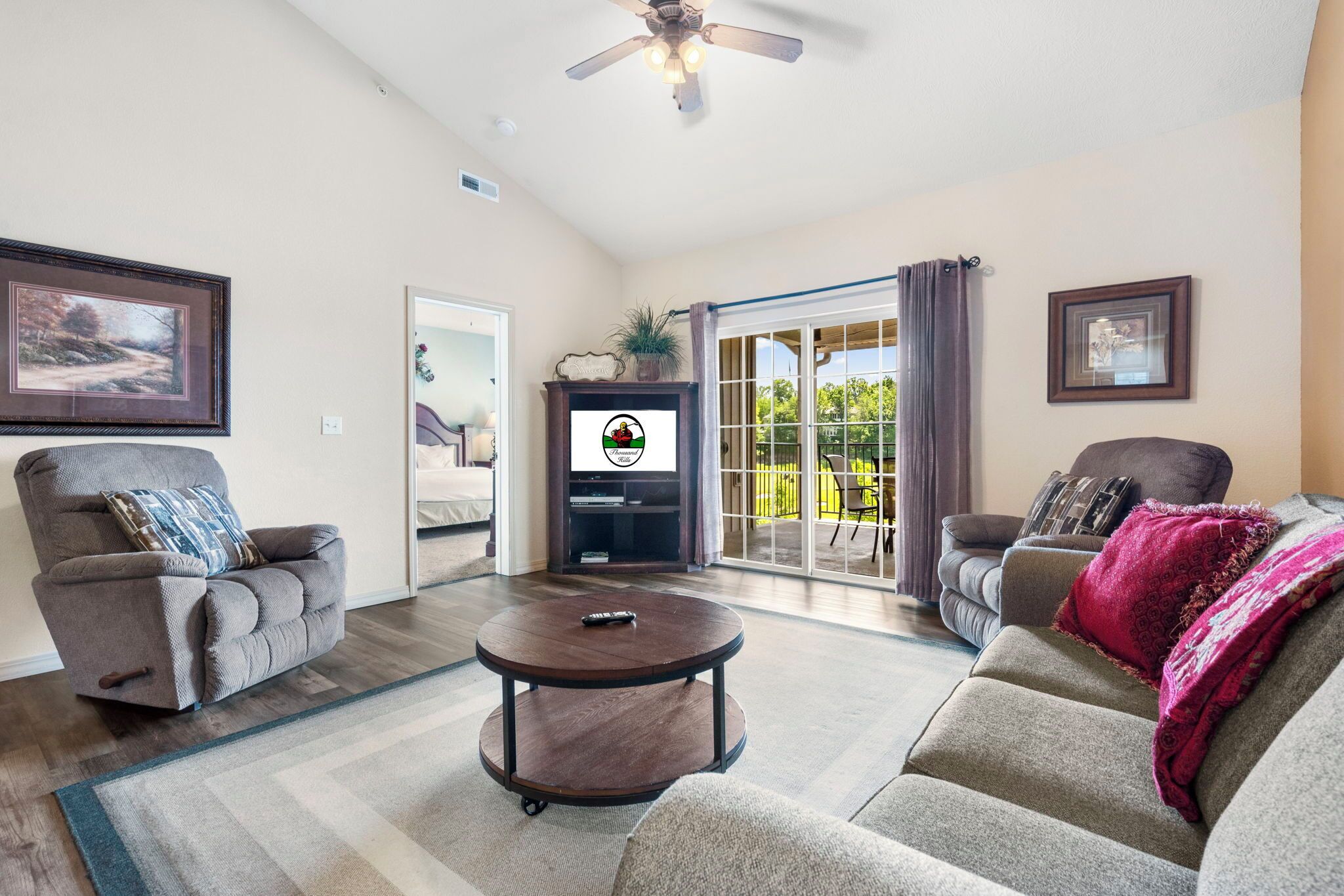 A living room with a sofa, armchairs, a coffee table, and a television.