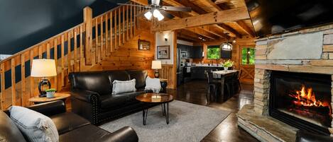 Una sala de estar acogedora con chimenea, una escalera y una zona de cocina.