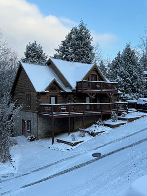 A log cabin with a balcony and a stone foundation. - Next to Rocky Top Sports! 5 King bedrooms 4 Bath Family-Friendly Sleeps 18 (Gatlinburg)