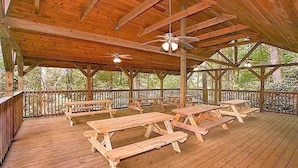 A covered wooden deck with picnic tables and ceiling fans. - Next to Rocky Top Sports! 5 King bedrooms 4 Bath Family-Friendly Sleeps 18 (Gatlinburg)