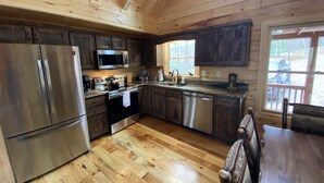 Cocina de cabaña de madera con refrigerador, microondas, estufa y lavavajillas de acero inoxidable.