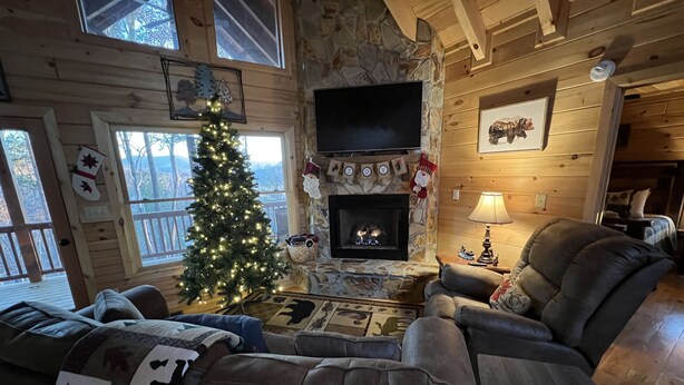 Un interior acogedor de cabaña con chimenea, un árbol de Navidad y una zona de estar confortable.