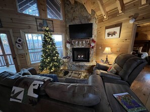 A cozy cabin interior with a fireplace, a Christmas tree, and a comfortable seating area. - Dog friendly, 2/2 w/kings, Mtn view! Fire pit, Wifi, gas logs. Cherry Log MTN !! (Cherry Log)