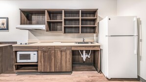 A modern kitchen with wooden cabinets, a built-in microwave, a stainless steel sink, and a white refrigerator. - Extended Stay America Select Suites Orlando Kissimmee (Kissimmee)