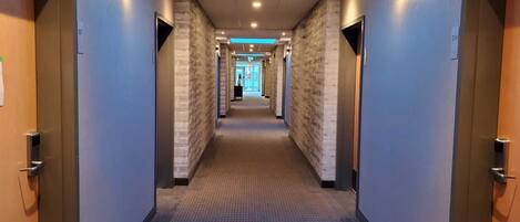 A hotel hallway with a skylight, carpeted floor, and doors numbered 307 and 314.