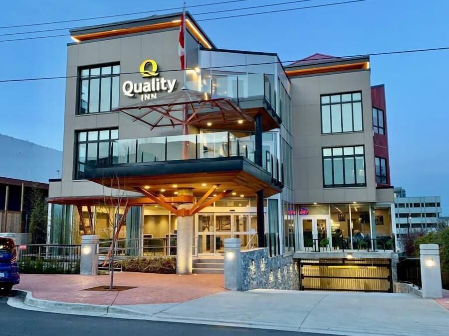A modern building with a glass facade and a sign reading "Quality Inn."