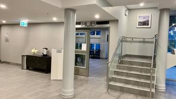 A modern lobby with a staircase, a reception desk, and a sign reading "THE HUB".