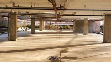 An empty parking garage with concrete pillars and exposed pipes.