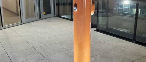 Un edificio moderno con entrada de vidrio y un gran pilar naranja.