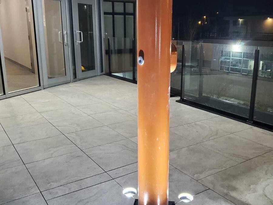 Un bâtiment moderne doté d’une entrée en verre et d’une grande colonne orange.