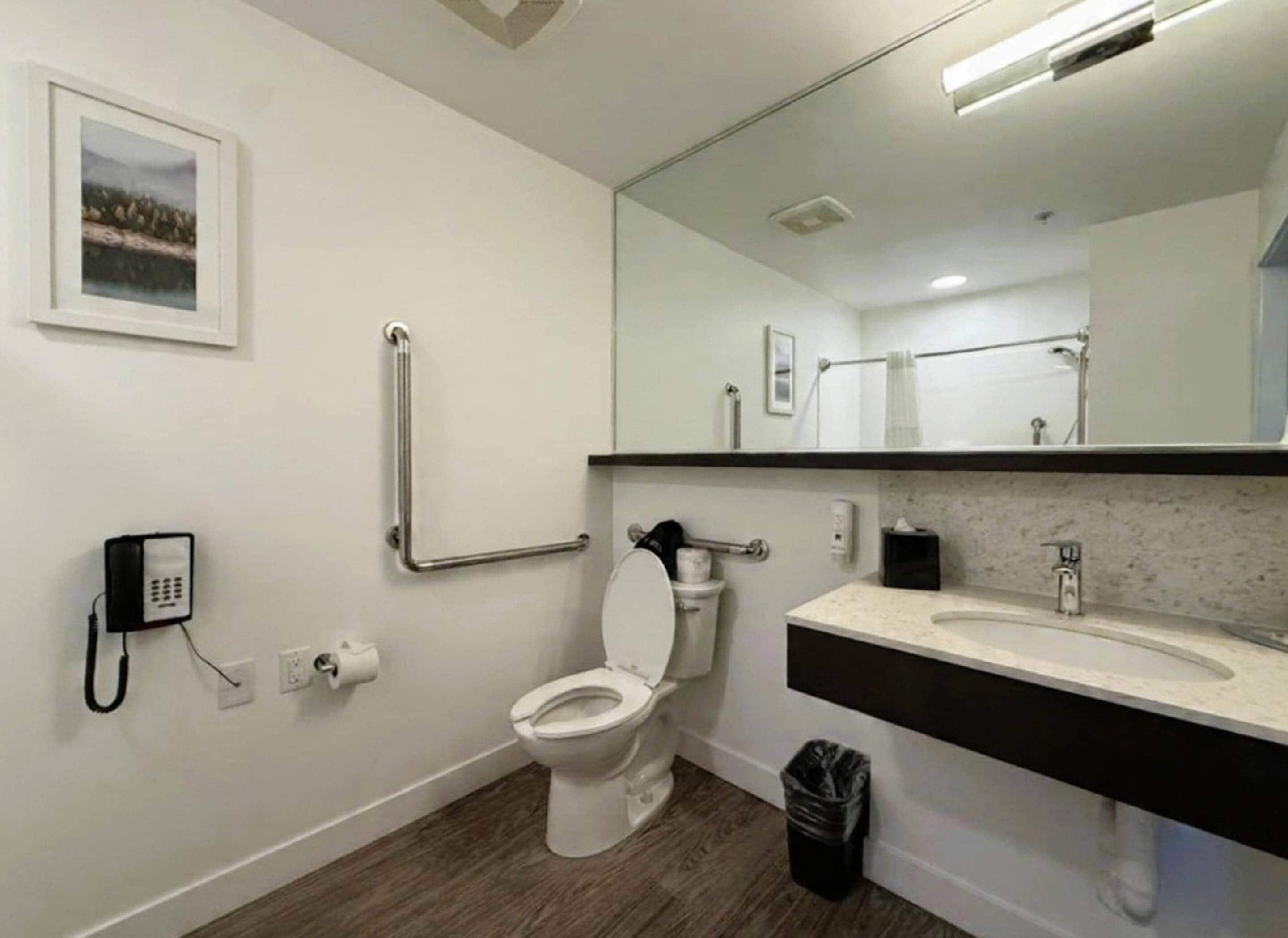 Un baño con inodoro, bidé, lavamanos, espejo y un cubo de basura.