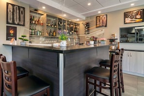 A bar area with a counter, seating, and a kitchen in the background.