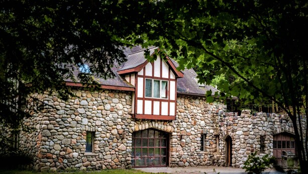A stone house with a Tudor-style window and a large arched entrance. - 'The Castle Gatehouse' of Highlands Castle (Bolton)