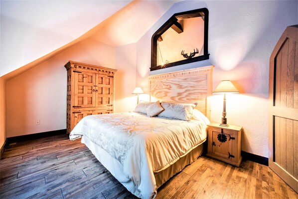 Une chambre avec un grand lit, une armoire en bois et une table de chevet avec des lampes.