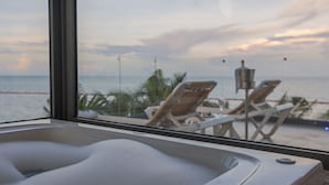 Una vasca idromassaggio con vista sull'oceano e sedie a sdraio.