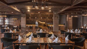 Un ristorante con tavoli e sedie in legno, un'area bar e una grande testa di animale appesa al muro.
