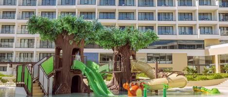 A hotel with a water park area featuring slides and artificial trees.
