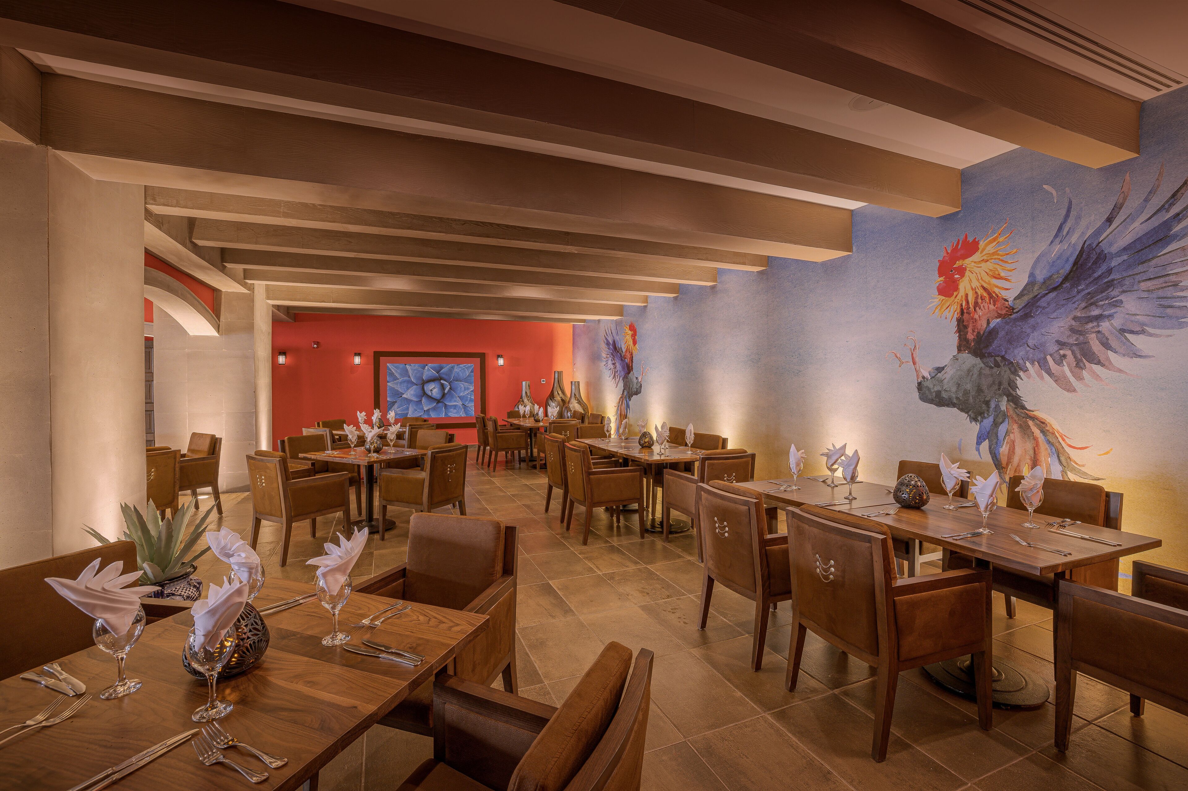 Un ristorante con tavoli e sedie in legno, una parete di accentazione rossa e un grande murale raffigurante un uccello.