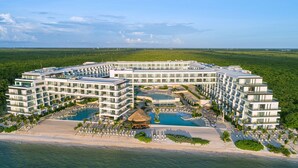 Un grande resort con diversi edifici, una piscina centrale e una spiaggia.