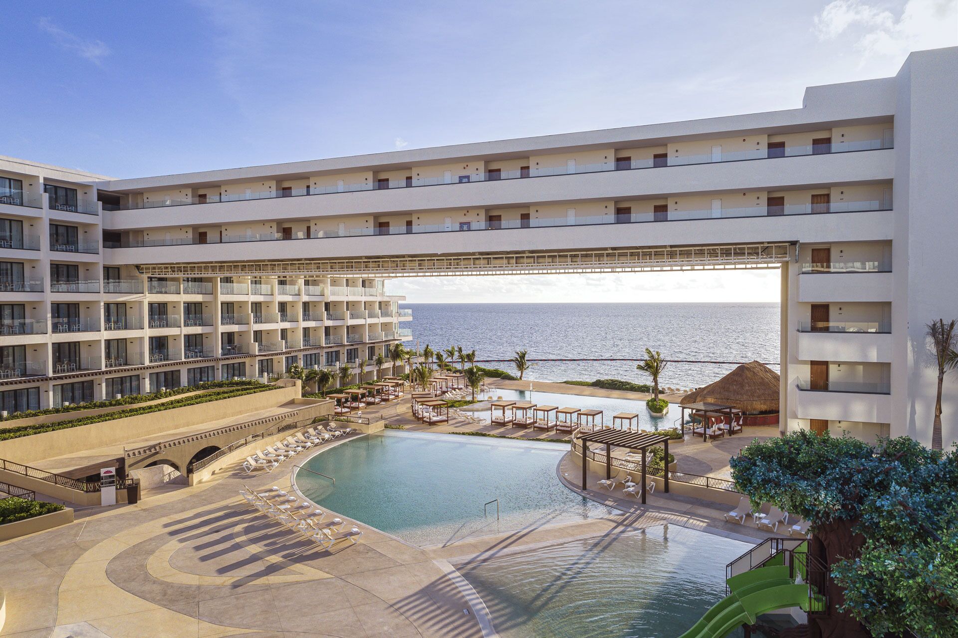 A hotel with multiple floors, a pool area, and a view of the ocean.