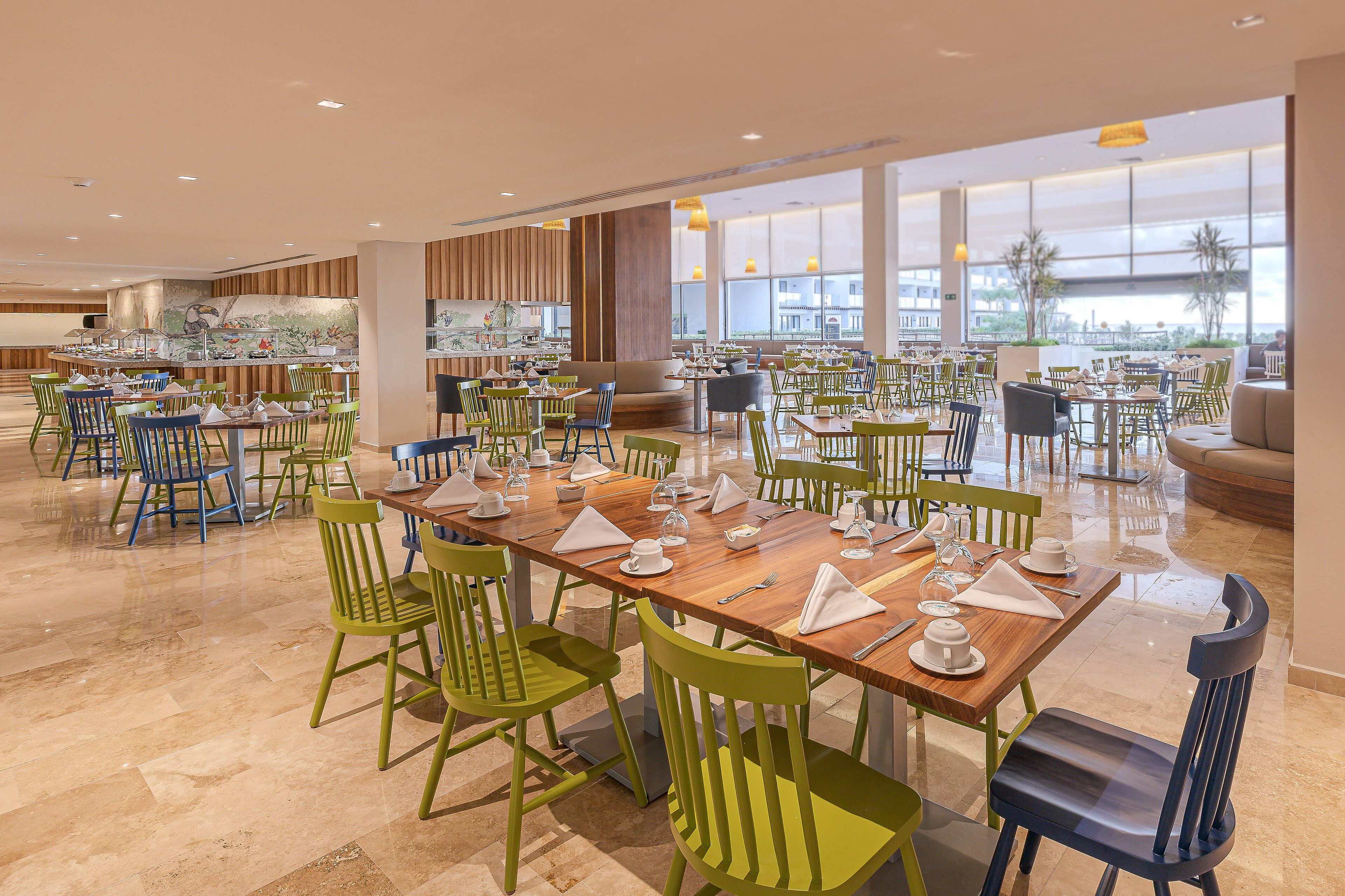 A spacious dining area with multiple tables and chairs, large windows, and a modern interior design.