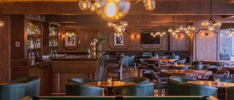 A bar area with pool tables, seating, and a bar stocked with bottles.