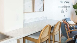 Una cocina moderna con encimera de mármol, sillas de madera y una pared con una cita motivacional.