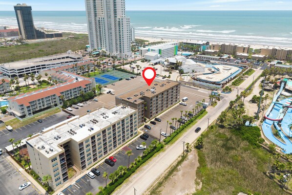 A multi-story hotel with a parking lot, adjacent to a beach and ocean view. - 1st Floor 1 Bedroom Condo near Beach  w/Pool!! (South Padre Island)