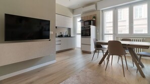 Una cocina moderna con un televisor de pantalla plana, un comedor con sillas y un ventanal grande.