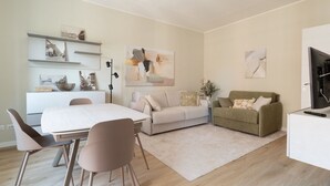 Una sala de estar moderna con comedor, un sofá, un televisor y obras de arte en las paredes.