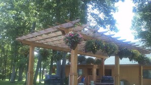 A wooden pergola with hanging flower baskets, a barbecue grill, and a picnic table in a backyard setting. - Dells Resort - Free Mini Golf + Kayaks + NO daily fee D (Dellona)