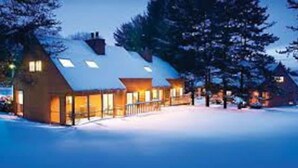 A row of wooden cabins with sloped roofs, surrounded by snow, and illuminated by warm lighting. - Dells Resort - Free Mini Golf + Kayaks + NO daily fee D (Dellona)